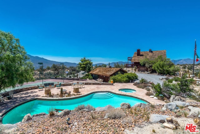 view of pool featuring an in ground hot tub, a mountain view, and a patio area