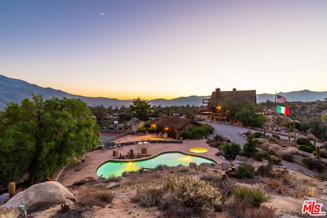 exterior space featuring a pool, a mountain view, and a patio area