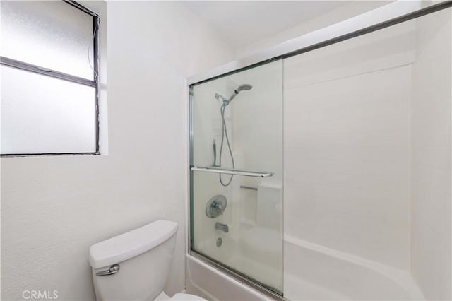 bathroom with toilet and shower / bath combination with glass door