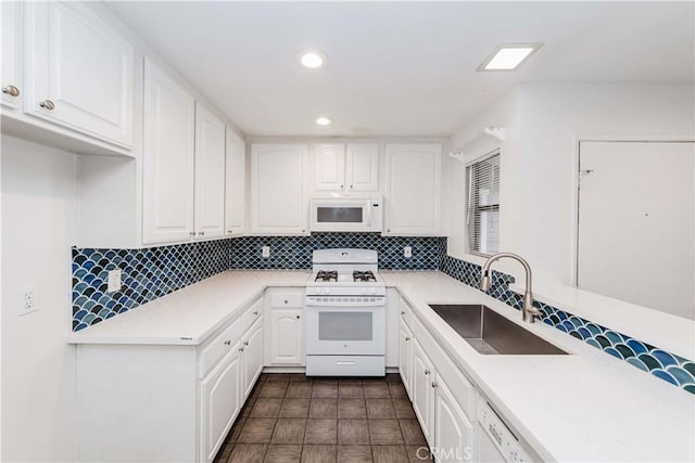 kitchen featuring a sink, white appliances, white cabinets, light countertops, and decorative backsplash