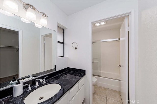 full bath featuring enclosed tub / shower combo, toilet, vanity, and tile patterned flooring