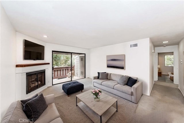 carpeted living area featuring recessed lighting, visible vents, and a fireplace