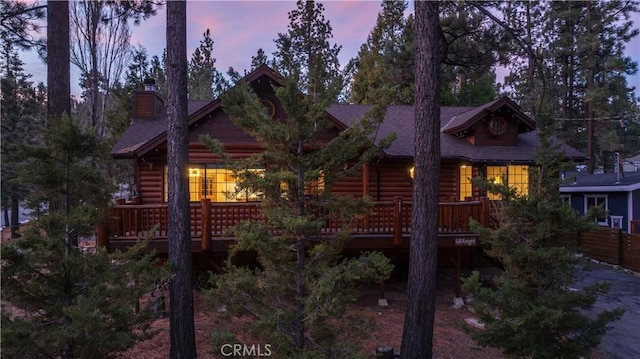 view of front of home featuring log veneer siding, a chimney, and a wooden deck