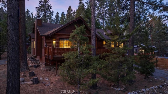 property exterior at dusk with faux log siding and a chimney