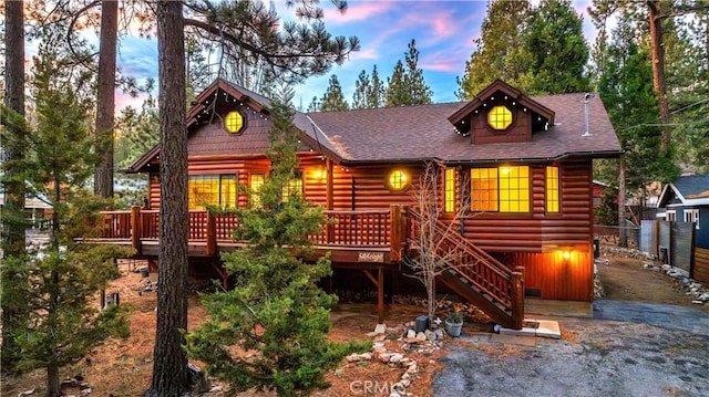 log cabin featuring stairway, roof with shingles, log veneer siding, and a wooden deck