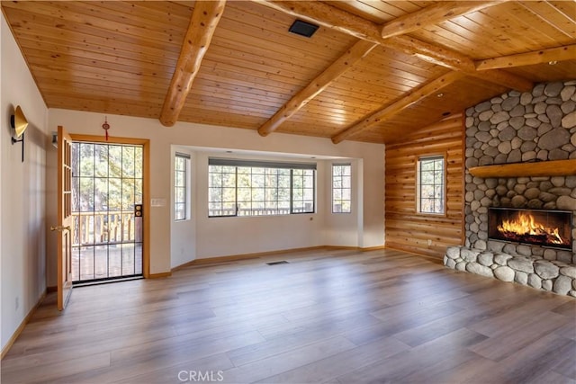 unfurnished living room featuring vaulted ceiling with beams, a stone fireplace, wooden ceiling, light wood-type flooring, and rustic walls