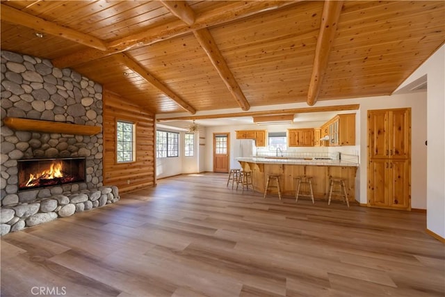 unfurnished living room featuring wood ceiling, light wood-style flooring, and a stone fireplace