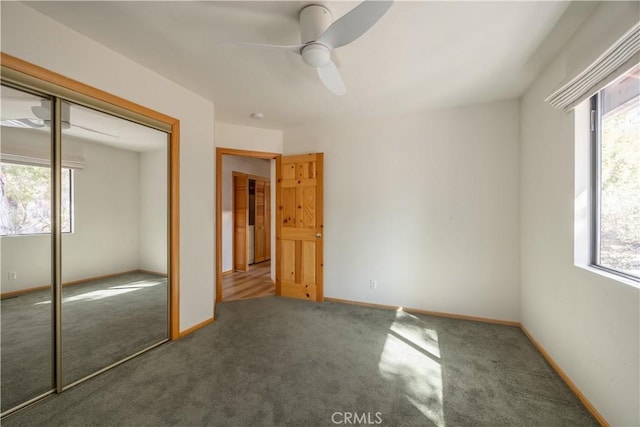 unfurnished bedroom featuring carpet floors, multiple windows, baseboards, and a closet