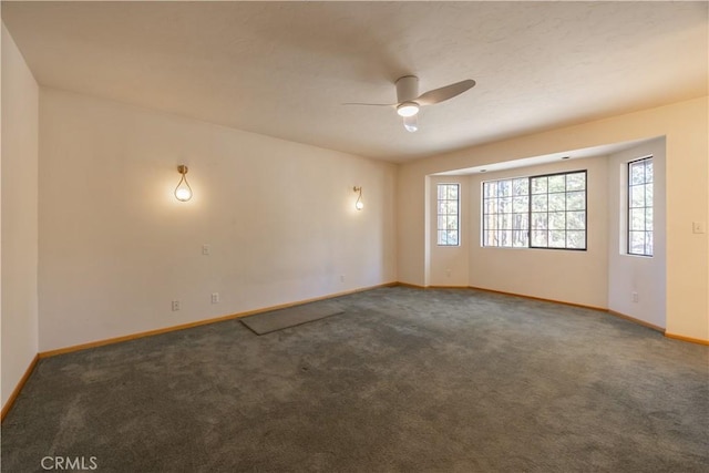 carpeted spare room featuring a ceiling fan, a wealth of natural light, and baseboards