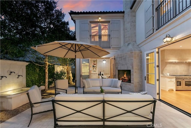 patio terrace at dusk with an outdoor living space with a fireplace