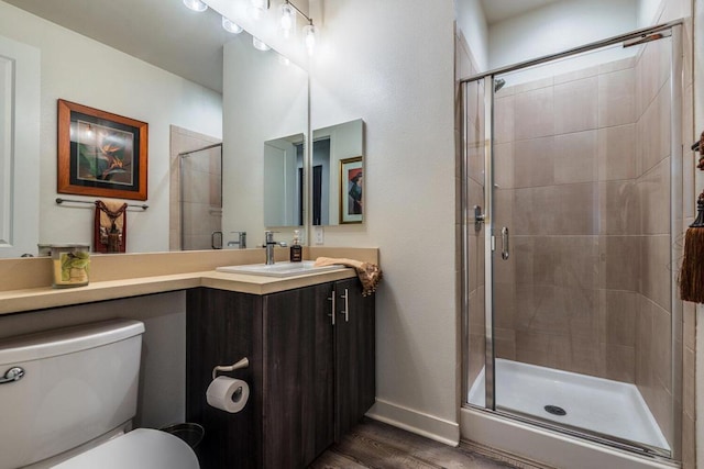 bathroom with walk in shower, hardwood / wood-style floors, vanity, and toilet