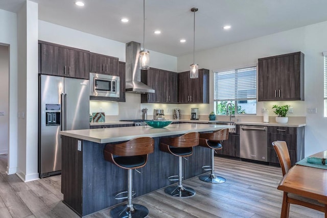 kitchen with dark brown cabinets, range hood, stainless steel appliances, a kitchen island, and decorative light fixtures