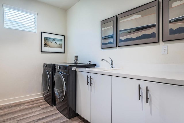 laundry area with cabinets, hardwood / wood-style floors, washer and dryer, and sink