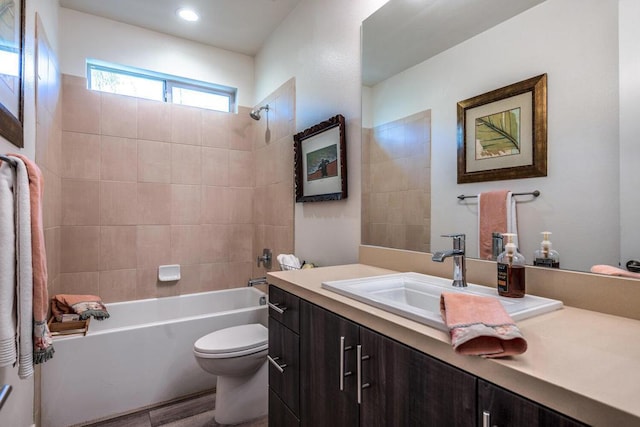 full bathroom featuring tiled shower / bath, vanity, and toilet