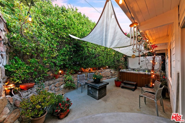 patio terrace at dusk with an outdoor fire pit and a hot tub