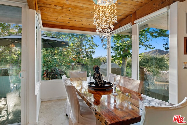 sunroom / solarium with a notable chandelier, a mountain view, and wooden ceiling