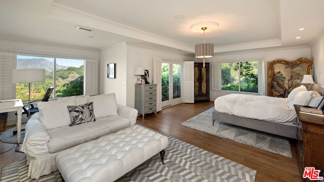 bedroom with a raised ceiling, crown molding, dark wood-type flooring, and multiple windows