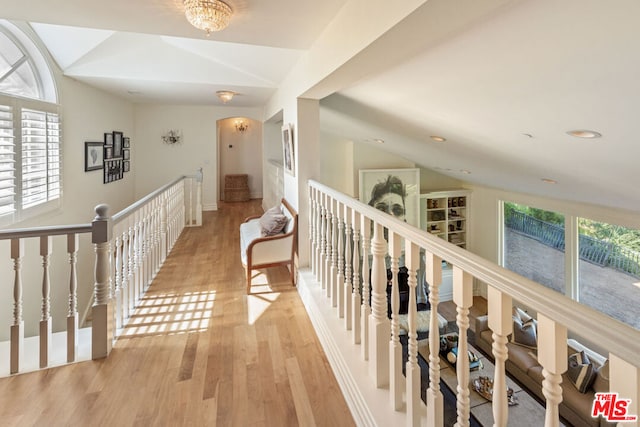 hallway with a healthy amount of sunlight, lofted ceiling, and light wood-type flooring