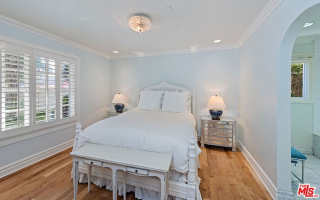 bedroom with ornamental molding, multiple windows, and light hardwood / wood-style flooring