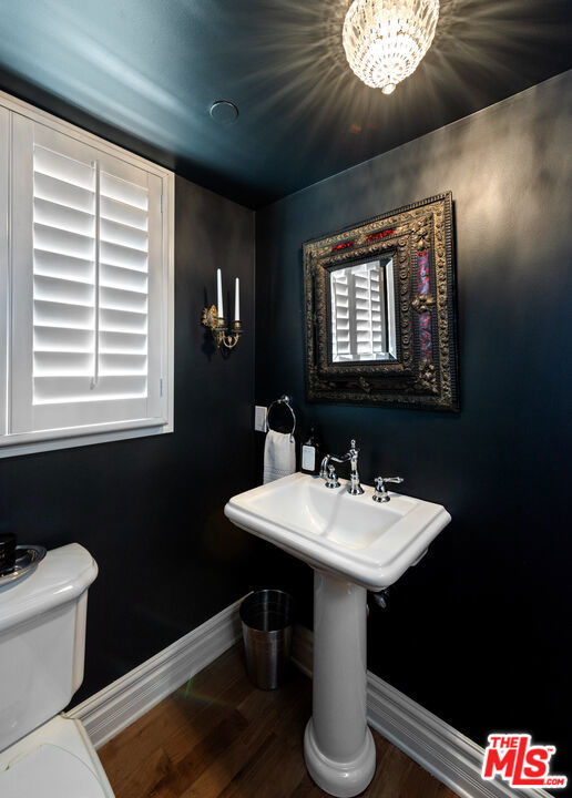 bathroom with hardwood / wood-style flooring, toilet, and a chandelier