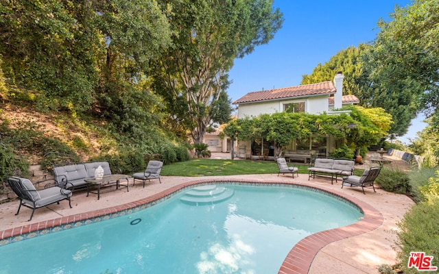 view of swimming pool with outdoor lounge area, a patio, and a lawn