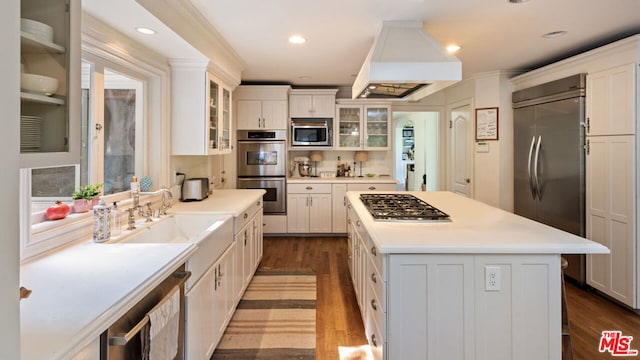 kitchen with premium range hood, white cabinetry, built in appliances, and a kitchen island