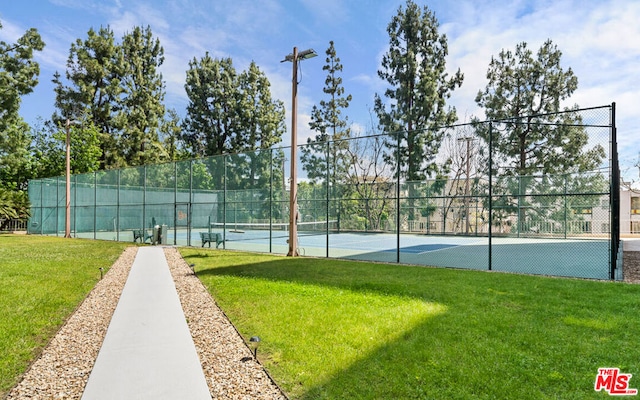 view of tennis court with a yard