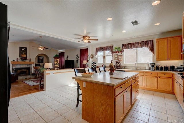 kitchen featuring vaulted ceiling, light tile patterned flooring, a kitchen island, and a kitchen bar