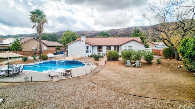 view of pool featuring an in ground hot tub, a mountain view, and a patio area