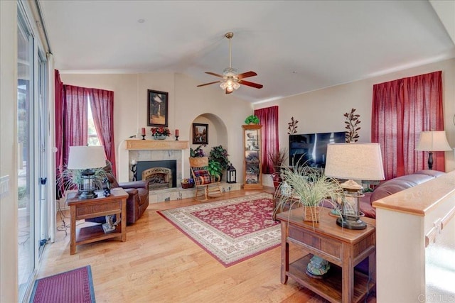 living room with vaulted ceiling, ceiling fan, a fireplace, and light wood-type flooring