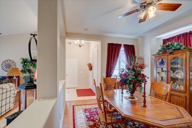 dining area with ceiling fan with notable chandelier and light hardwood / wood-style floors