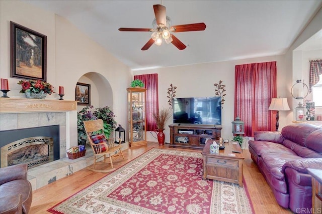 living room with a tile fireplace, vaulted ceiling, hardwood / wood-style floors, and ceiling fan