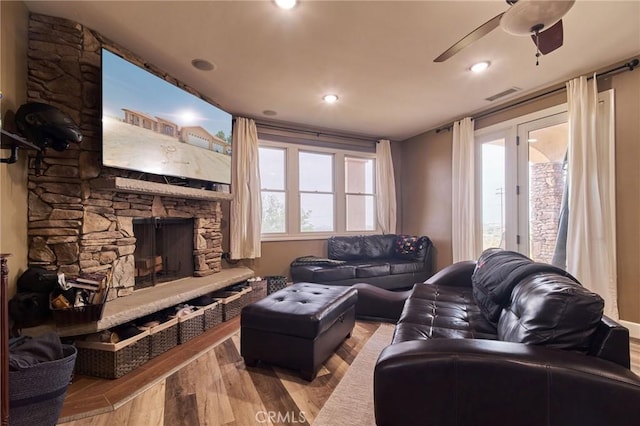 living room featuring a fireplace, ceiling fan, and light wood-type flooring