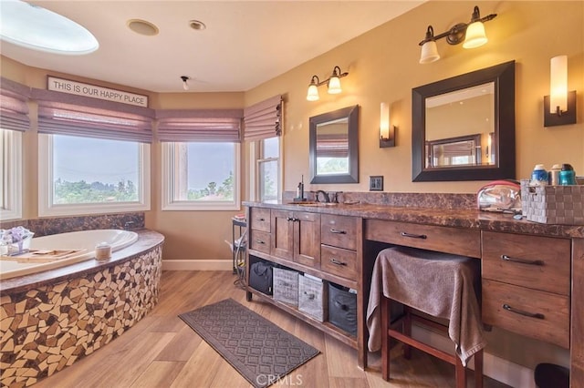 bathroom featuring a relaxing tiled tub, vanity, and hardwood / wood-style floors