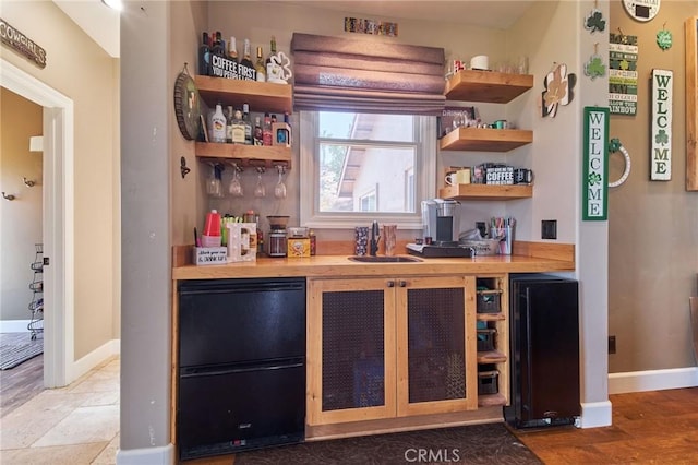 bar featuring sink and black refrigerator