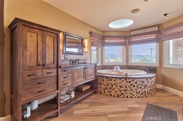 bathroom with vanity, hardwood / wood-style floors, and tiled bath