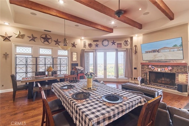 dining space featuring hardwood / wood-style floors, a stone fireplace, french doors, and beamed ceiling