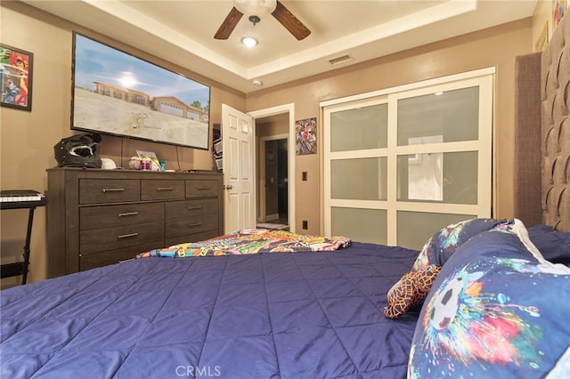 bedroom with ceiling fan and a raised ceiling