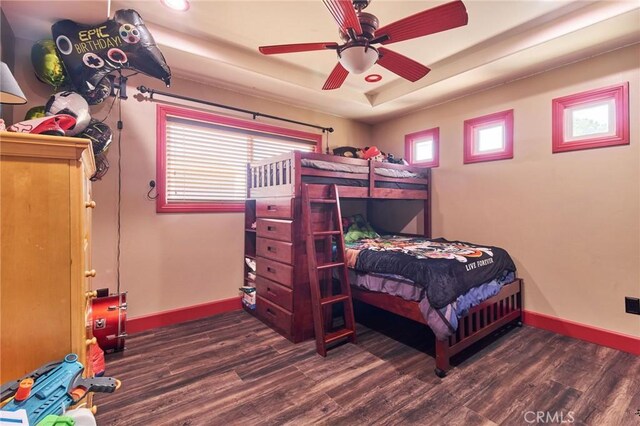 bedroom featuring dark hardwood / wood-style flooring, multiple windows, and a raised ceiling