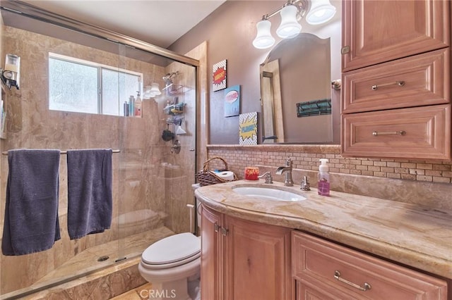 bathroom with vanity, decorative backsplash, a shower with door, and toilet