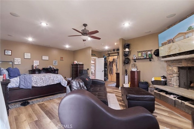 living room with ceiling fan, a fireplace, and light hardwood / wood-style flooring