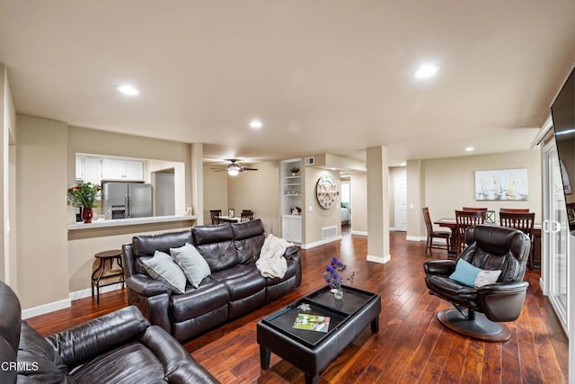 living room featuring dark wood-type flooring and ceiling fan