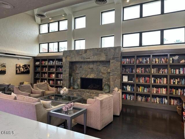 living room with a towering ceiling, a fireplace, built in shelves, and wood-type flooring