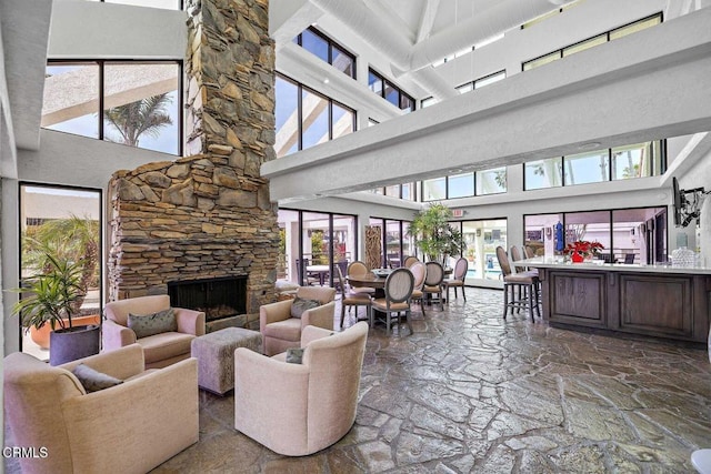 living room featuring a stone fireplace and a high ceiling