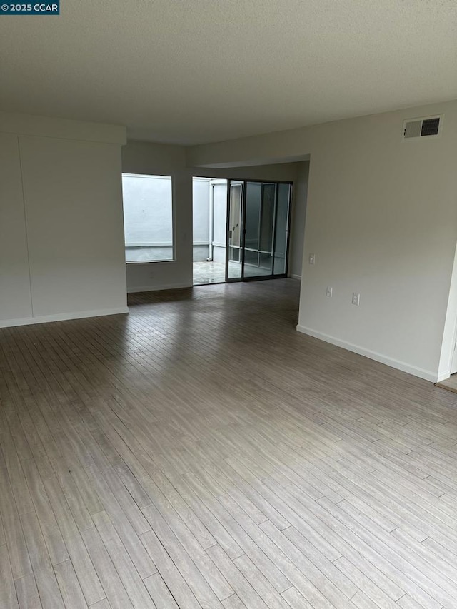 empty room featuring a textured ceiling and light hardwood / wood-style flooring