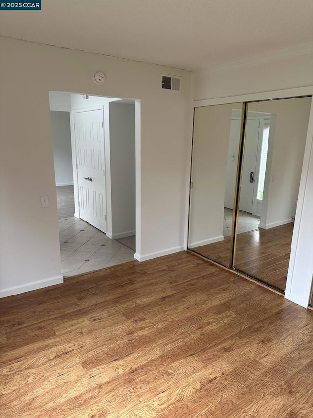 unfurnished bedroom with light hardwood / wood-style flooring and a closet