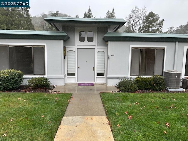 entrance to property featuring a yard and central AC