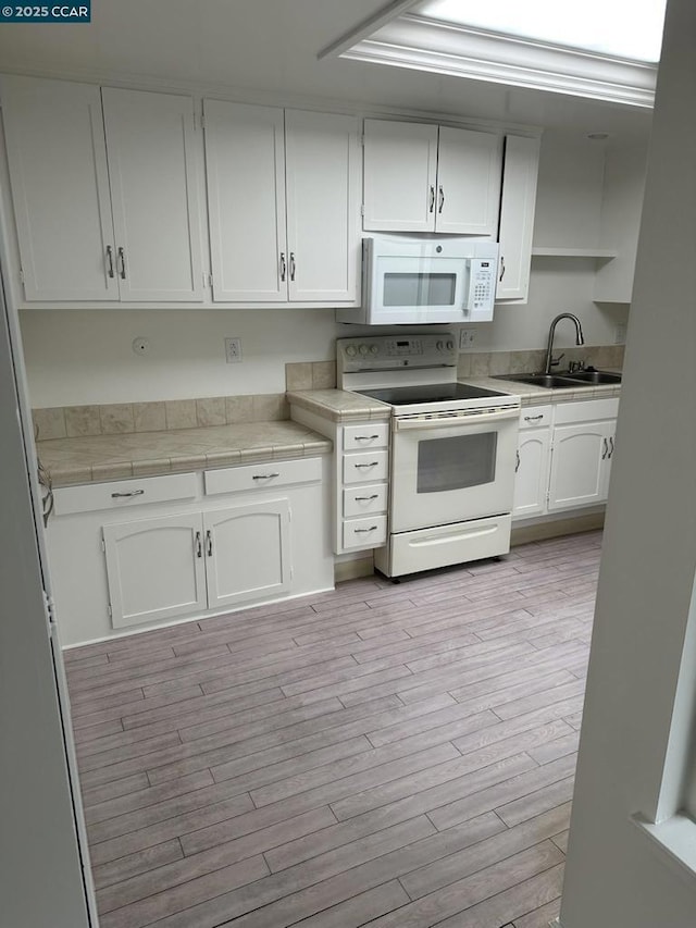 kitchen featuring sink, white cabinets, white appliances, and light hardwood / wood-style floors