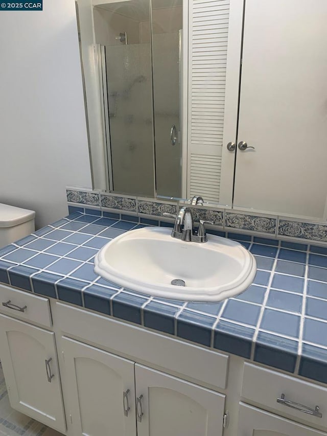 bathroom featuring vanity, toilet, and a shower with shower door