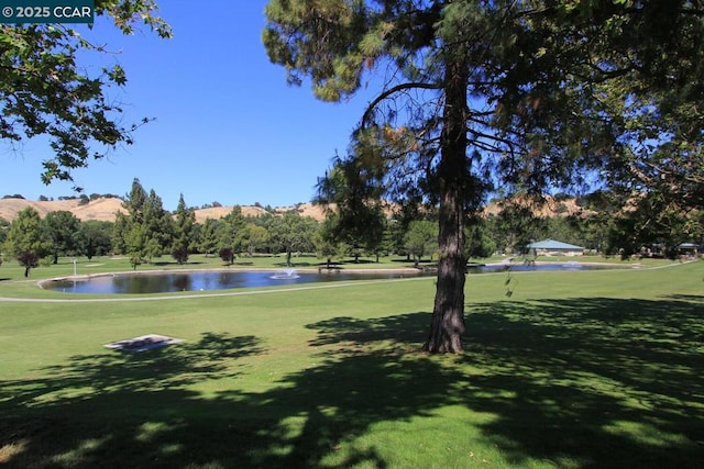 surrounding community with a water and mountain view and a lawn